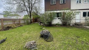 Ein Wohngrundstück mit Rasen, Holzzaun und einem Haus mit zwei Fenstern.