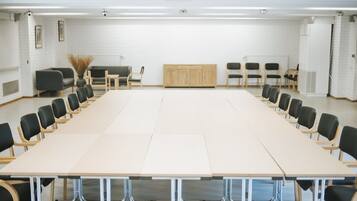 A conference room with a long table and chairs, white brick walls, and a projector.