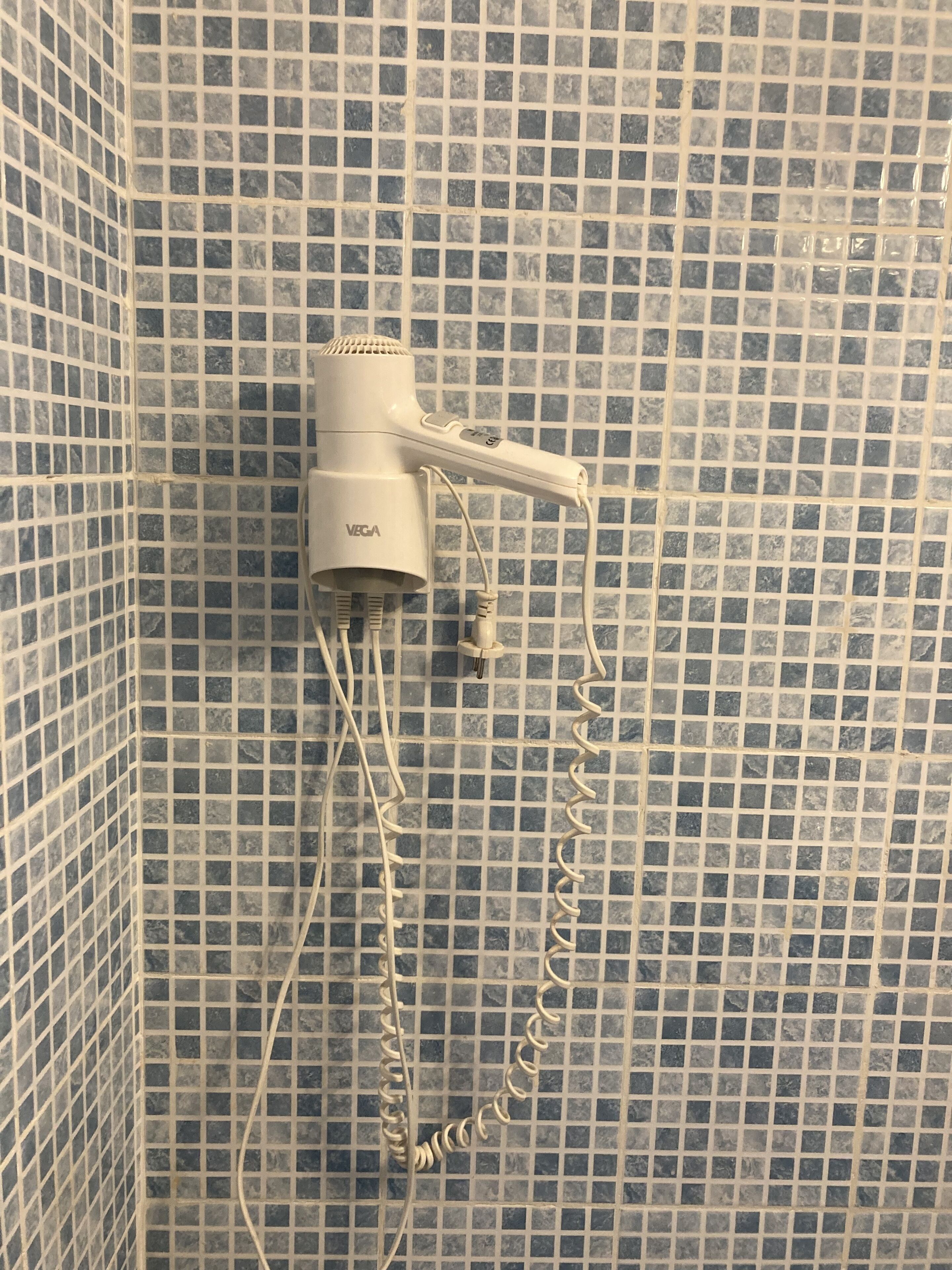 Ein Fön an einer gefliesten Wand.