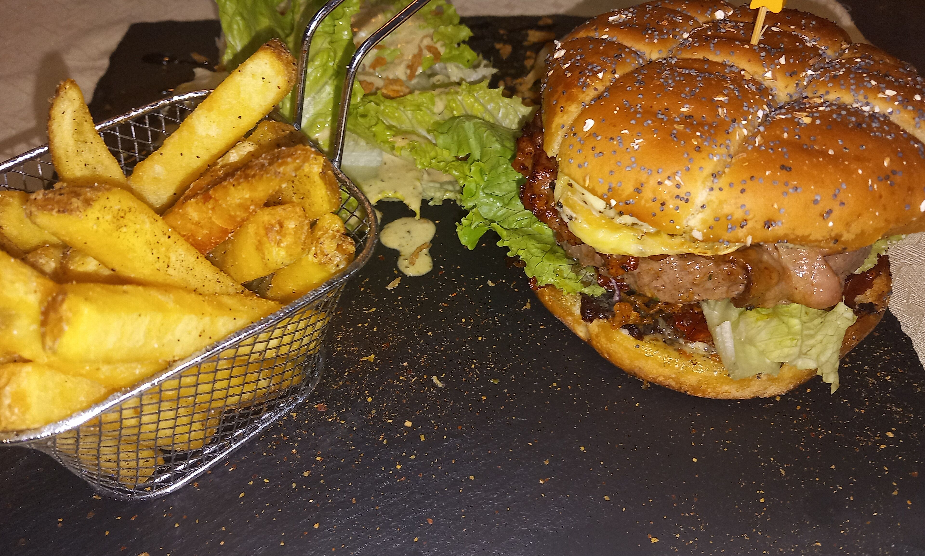 A basket of French fries and a burger with lettuce and a bun.