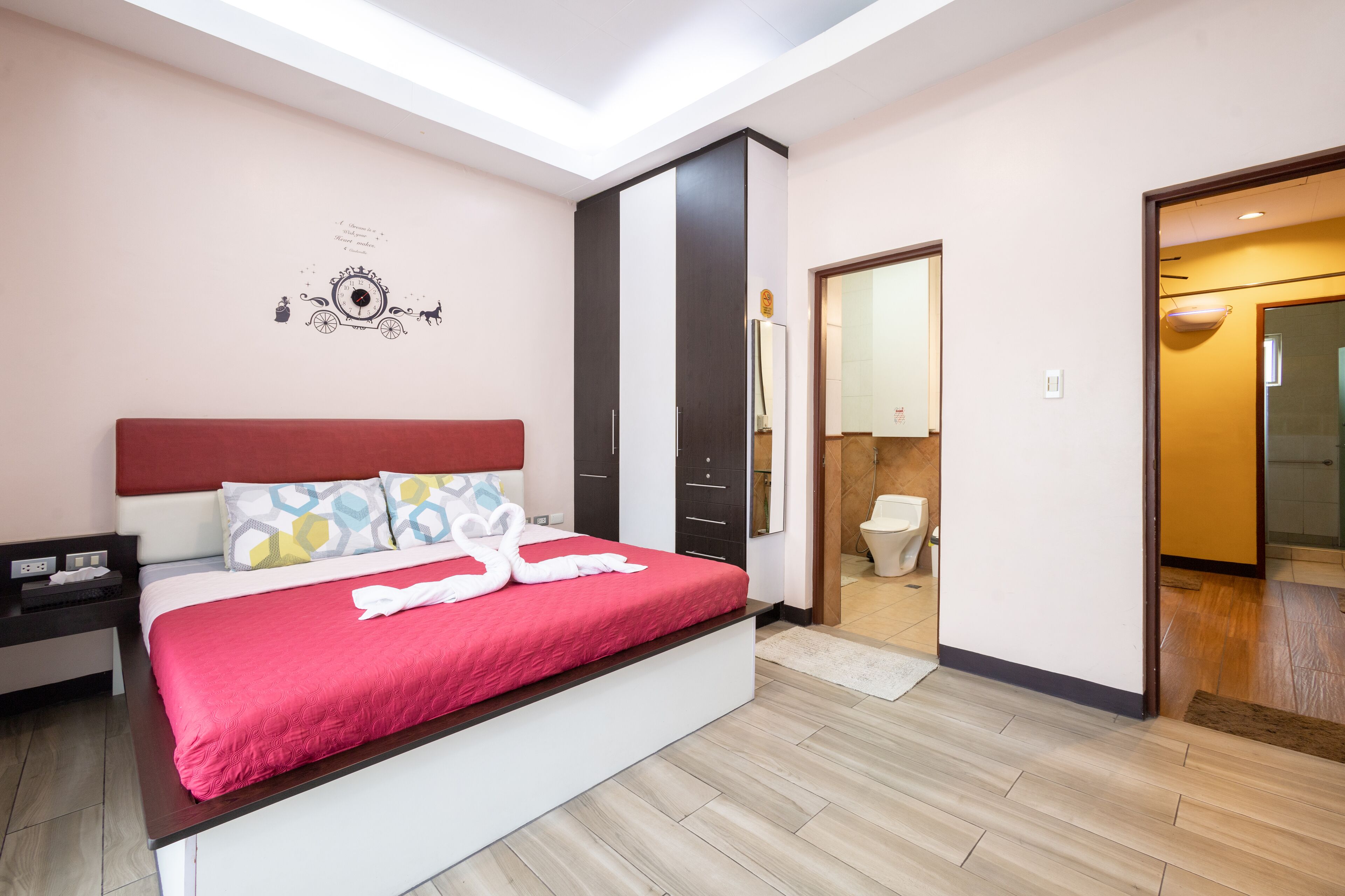 A modern bedroom with a large bed, a nightstand, a wardrobe, and a bathroom visible through an open door.