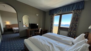 A hotel room with a bed, a desk with a computer, a television, and a window with curtains. - PanoramaHotel Penegal (Ruffre)