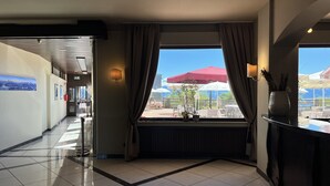 A hotel lobby with a view of the outdoor terrace, a reception desk, and a tiled floor. - PanoramaHotel Penegal (Ruffre)
