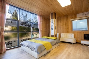 A modern bedroom with a large window, wooden ceiling, and a bed with a yellow throw blanket. - Gapyeong Yeolhodang Pension (Gapyeong)