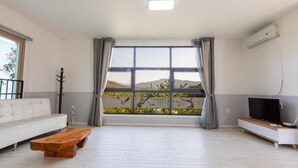 A spacious living room with a large window, a white sofa, a wooden coffee table, and a TV on a white cabinet. - Gapyeong Yeolhodang Pension (Gapyeong)