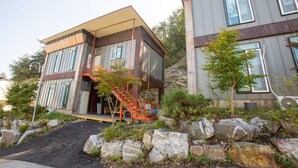 A modern two-story building with a wooden facade, large windows, and a red staircase leading to the entrance. - Gapyeong Yeolhodang Pension (Gapyeong)