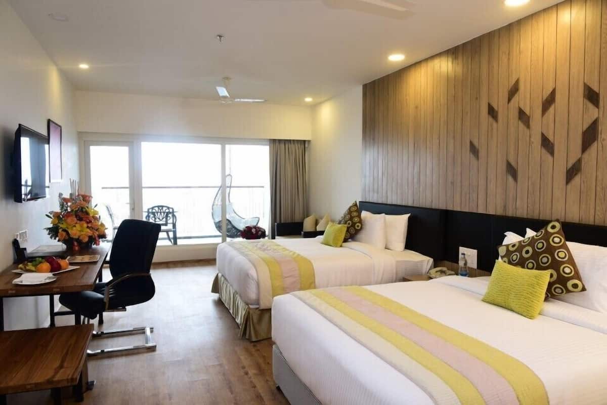 Ein Hotelzimmer mit zwei Betten, einem Schreibtisch mit Stuhl, einem Esstisch und einem Balkon mit Sitzgelegenheit.