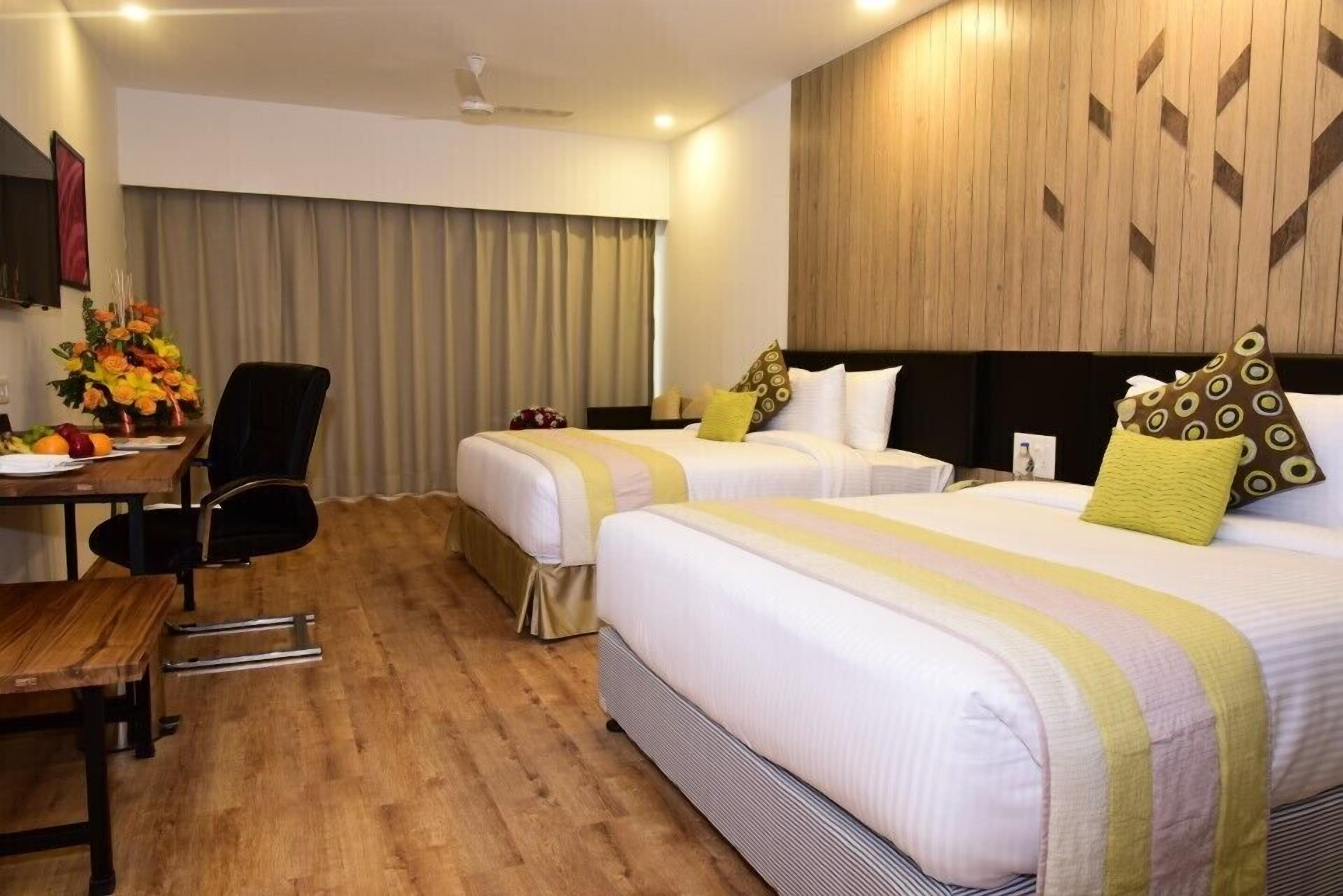 A hotel room with two beds, a desk, and a chair.