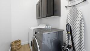 Un espace dédié à la lessive, comprenant un lave-linge, un étendoir et un aspirateur.