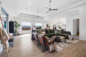 A spacious living room with a large sectional sofa, a coffee table, and a dining area with a view of the mountains.