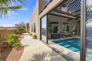 A modern outdoor pool area with a clear view of the pool, lounge chairs, and a pergola structure.