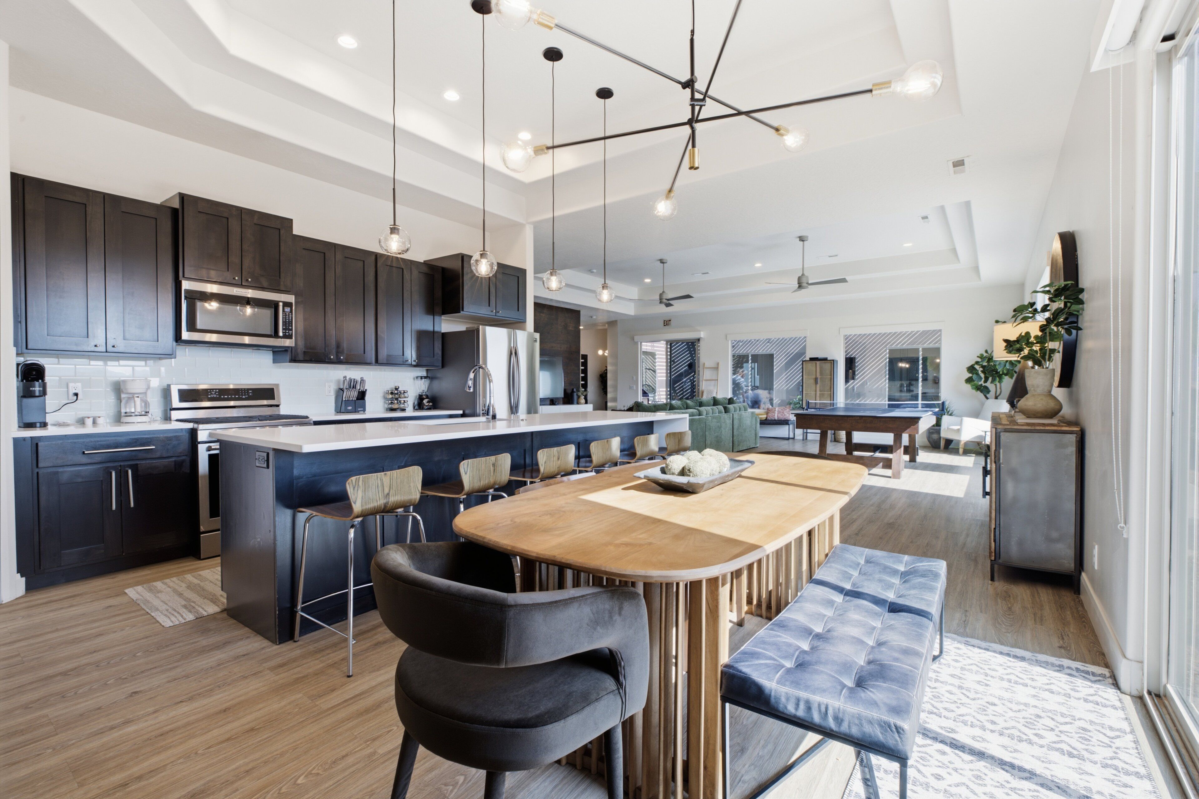 A modern kitchen with dark cabinetry, a central island with bar stools, and pendant lighting.