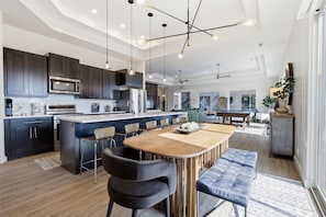 A modern kitchen with dark cabinetry, a central island with bar stools, and pendant lighting.