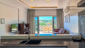 A modern kitchen with a built-in dishwasher, a flat-screen TV, and a large window overlooking a scenic view.