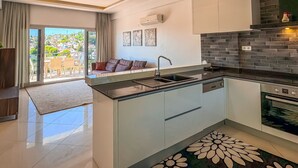 A modern kitchen with a central island, a built-in oven, and a large window overlooking a cityscape.
