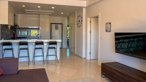 A modern living room with a sofa, a TV, and a kitchen area with a bar.