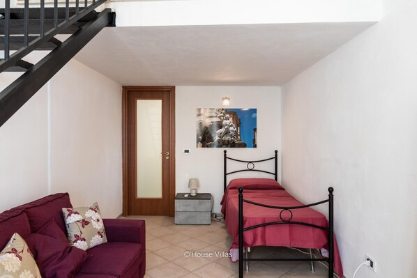 A compact bedroom with a bed, a sofa, and a staircase. - Ciuri Ciuri in Noto With 3 Bedrooms and 2 Bathrooms (Noto)