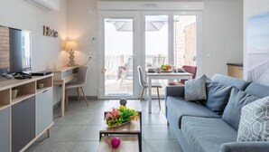 A modern living room with a sofa, TV, and a dining area with a table and chairs. - Apartment SC H01 by Interhome (Mimizan)