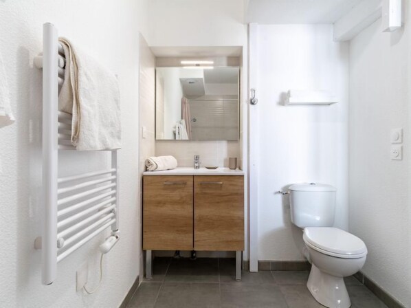 Une salle de bain moderne avec un porte-serviettes, un meuble-lavabo en bois, un miroir et des toilettes.