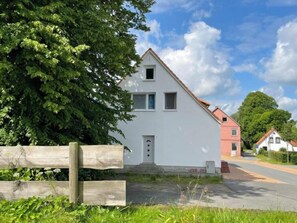 A two-story white house with a red roof, a wooden fence in the foreground, and a clear sky. - Am Ostedeich by Interhome (Wingst)
