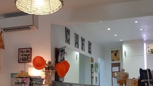 A cafe interior with a wooden counter, stools, and a hanging light fixture.