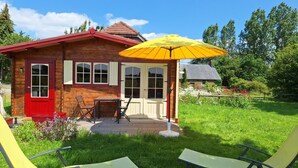 A wooden cabin with a red door, a yellow umbrella, and two lounge chairs in the yard. - Intimate, sunny châlet for 2 people in southern Normandy (Saint-Mars-d'Égrenne)