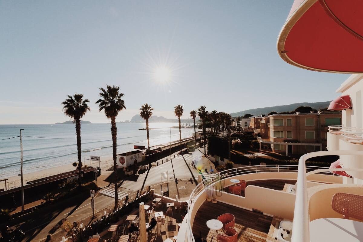 A balcony with a view of the beach, palm trees, and ocean.