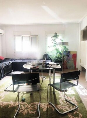 A living room with a sofa, a coffee table, two chairs, and a plant.