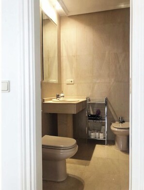 A bathroom with a toilet, sink, and bidet.