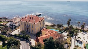Un bâtiment situé sur la côte, doté d’un toit recouvert de tuiles rouges, d’une piscine et offrant une vue sur l’océan.