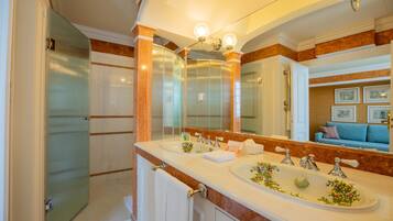 A bathroom with a large mirror, two sinks, and a shower.