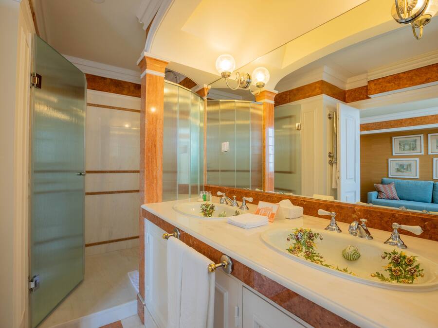 A bathroom with a large mirror, two sinks, and a shower.
