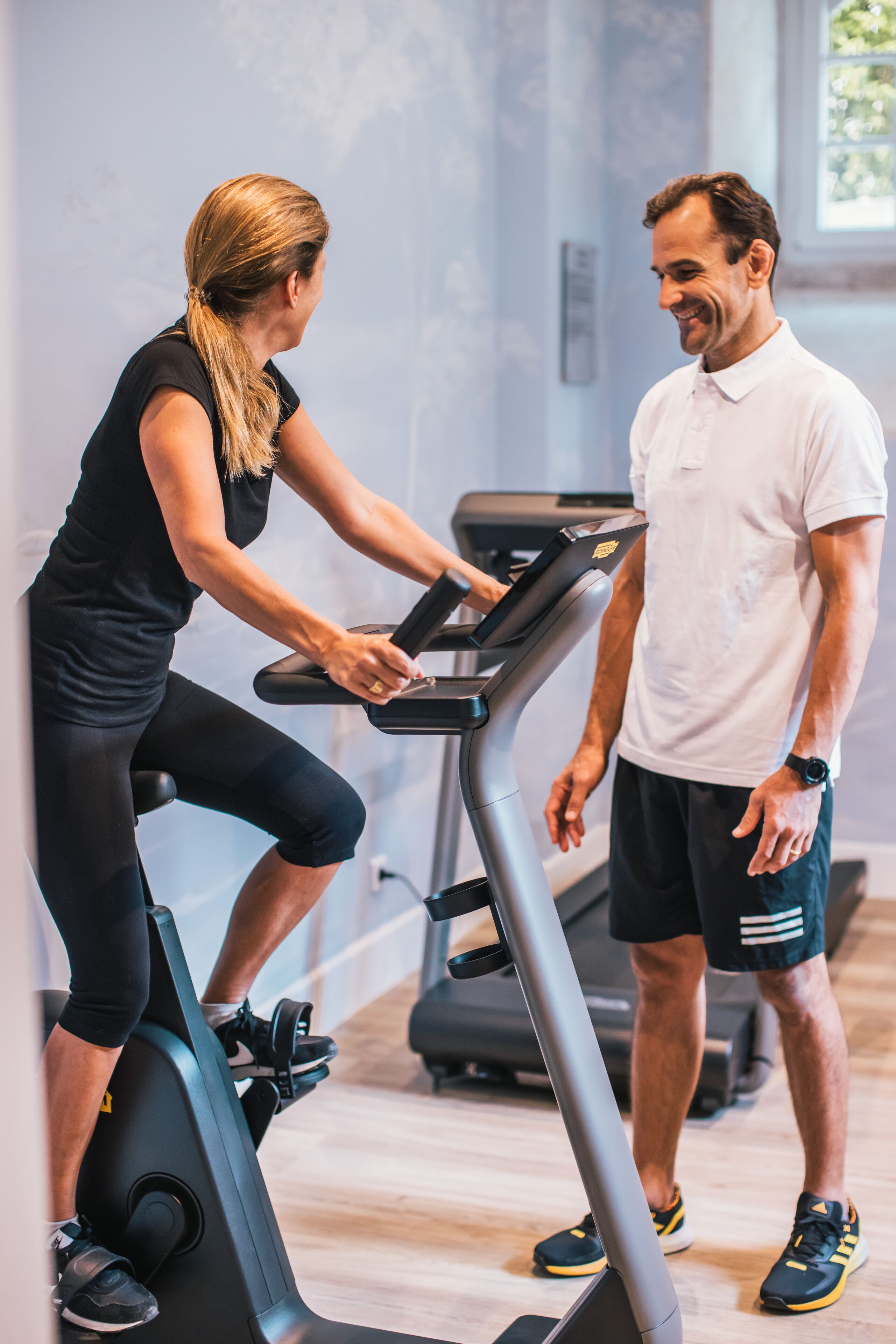 Une salle de sport équipée de matériel d’exercice, notamment un tapis de course et des vélos d’appartement.