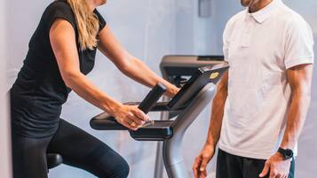 Une salle de sport équipée de matériel d’exercice, notamment un tapis de course et des vélos d’appartement.