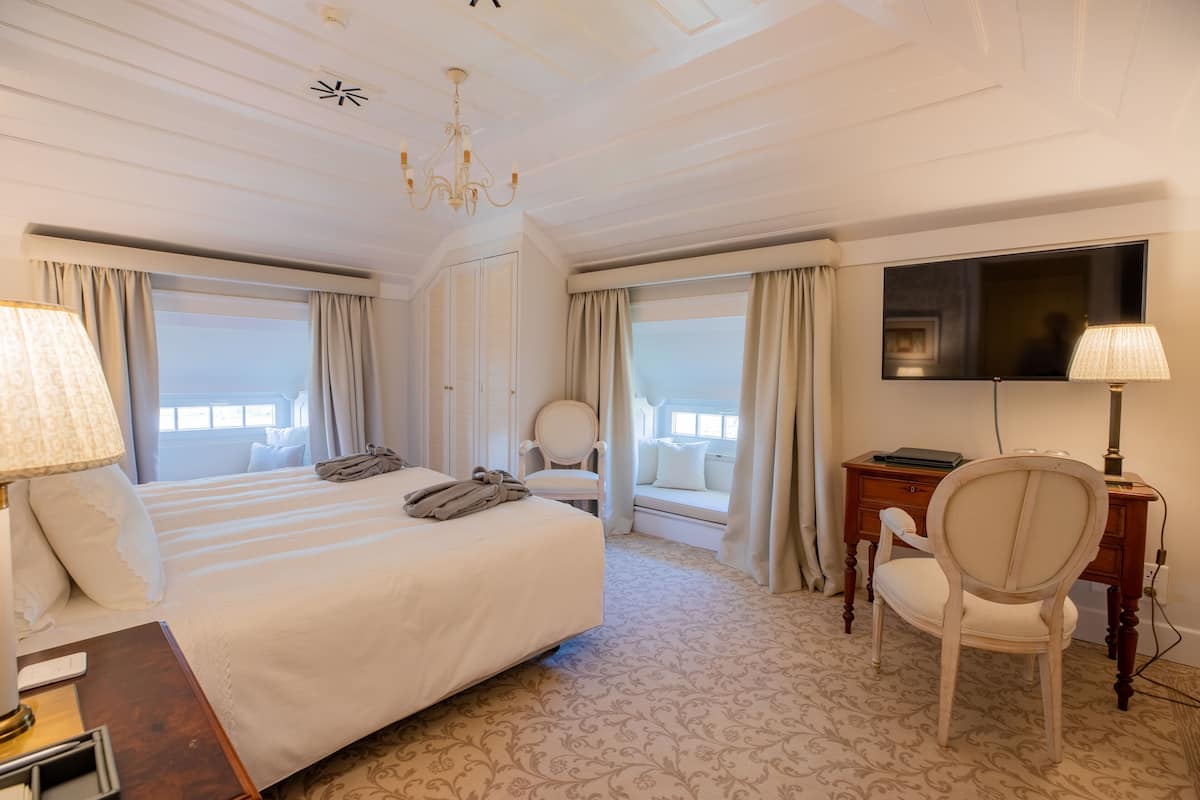 Een hotelkamer met een bed, een bureau met stoel, een televisie en een raam met gordijnen.