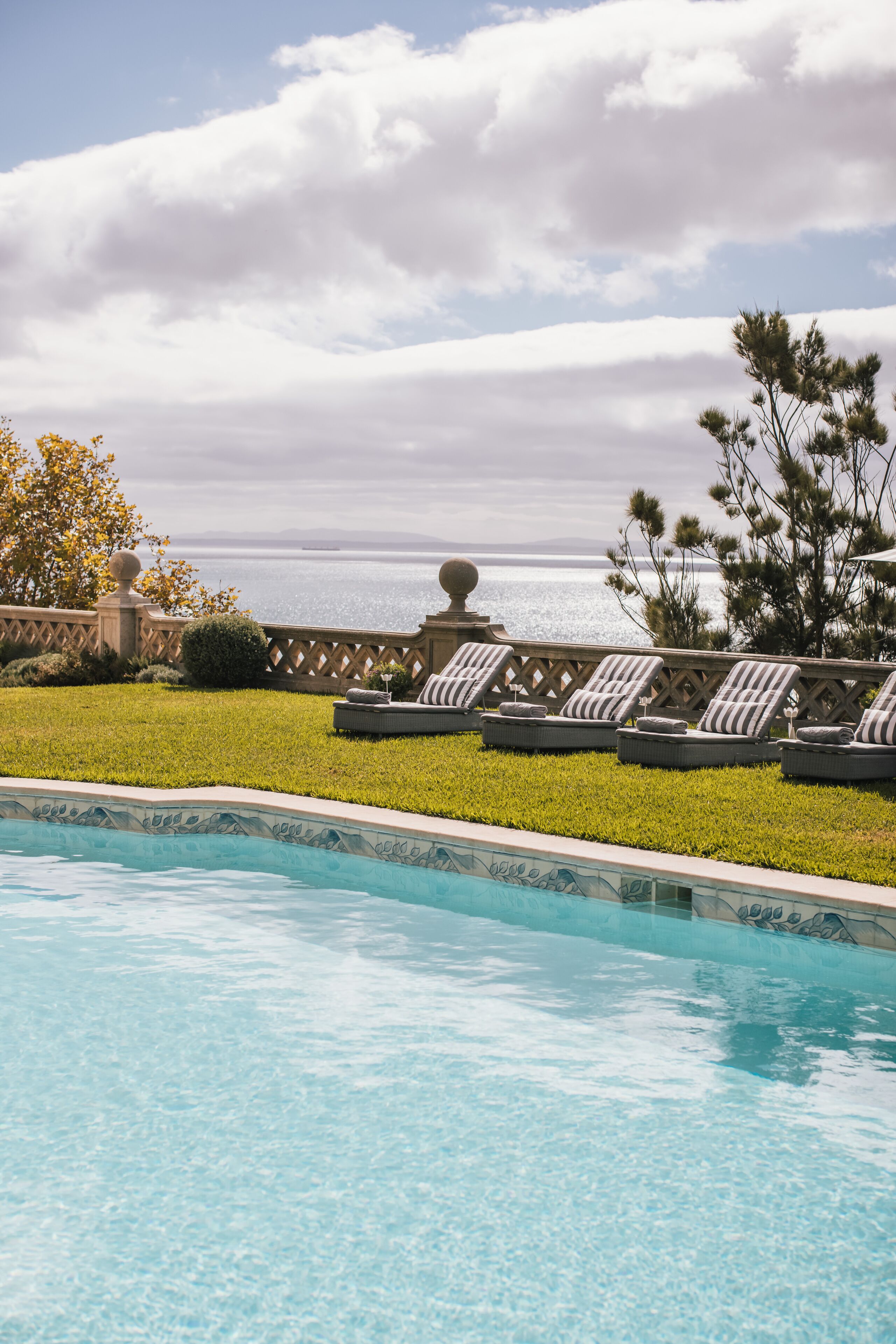 Une piscine avec des chaises longues et vue sur l’océan.