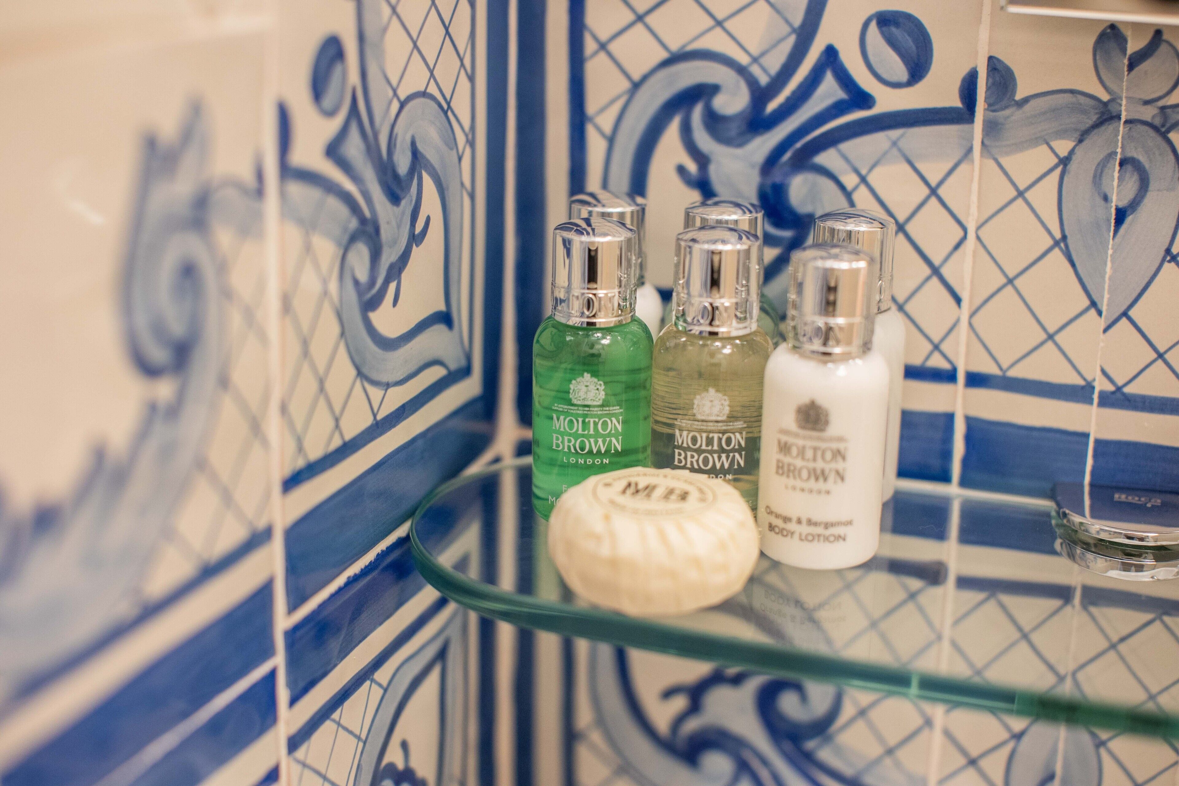 A bathroom shelf with three bottles of Molton Brown London body lotion and a soap bar.