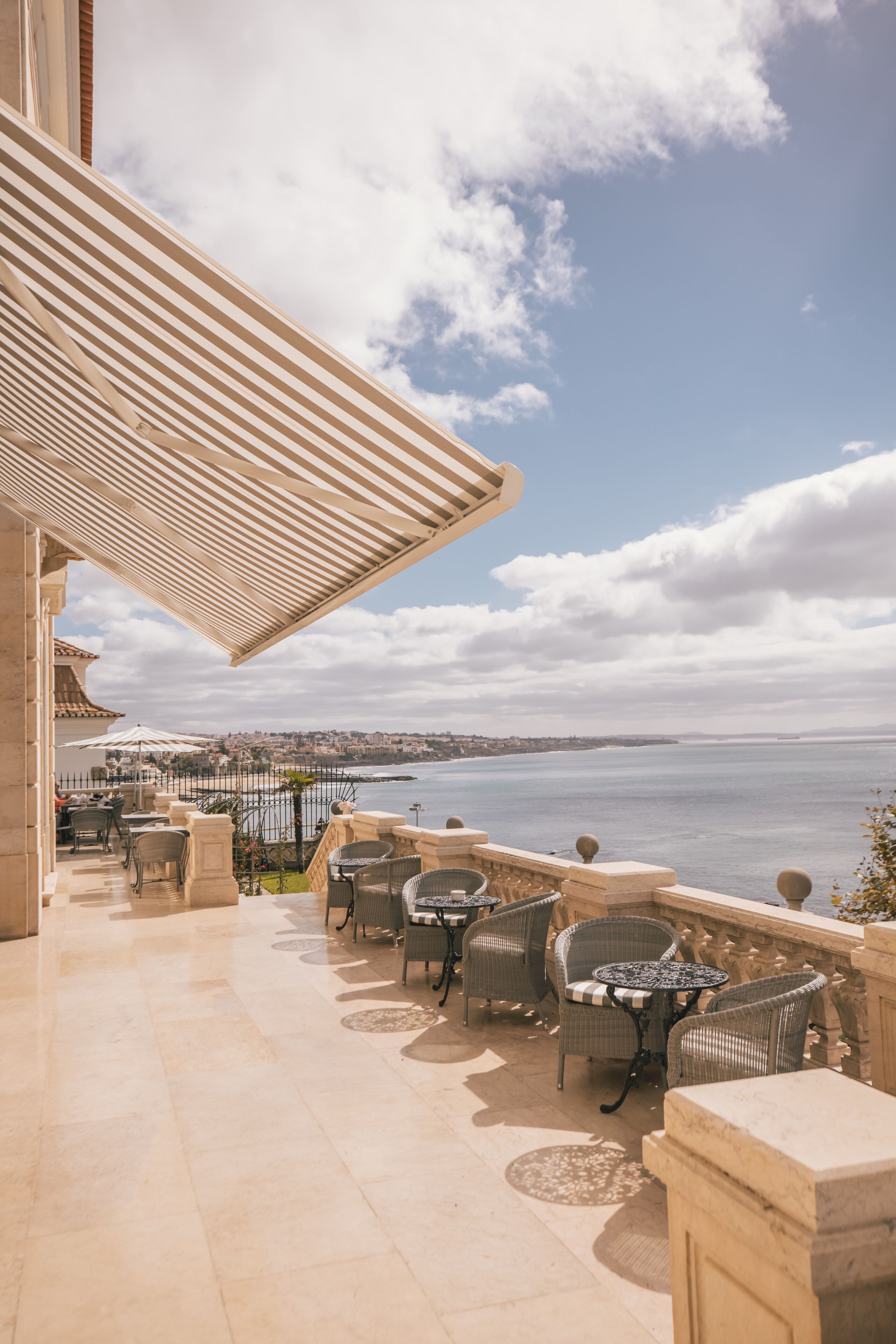 Una terraza con mesas al aire libre, vista al mar y cielo despejado.