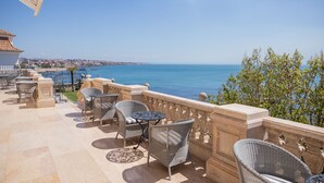 Une terrasse dotée de mobilier en osier et offrant une vue sur la mer.