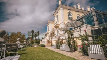 A historic building with a garden patio, outdoor seating, and a glass conservatory.
