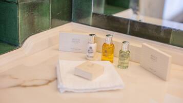 A bathroom with a white marble sink, a mirror, and toiletries including a shower cap, body lotion, and two bottles of liquid.