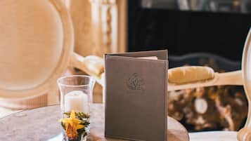 A round table with a leather wallet, a glass candle holder with a candle, and a small vase with flowers.