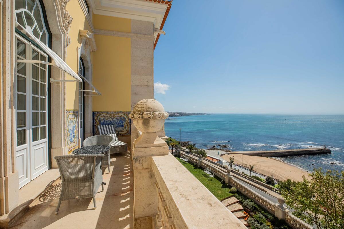 Ein Balkon mit Korbmöbeln Blick auf Strand und Meer.