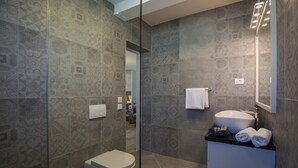 Un baño moderno con baldosas estampadas, un inodoro, un lavamanos con espejo y un perchero para toallas.