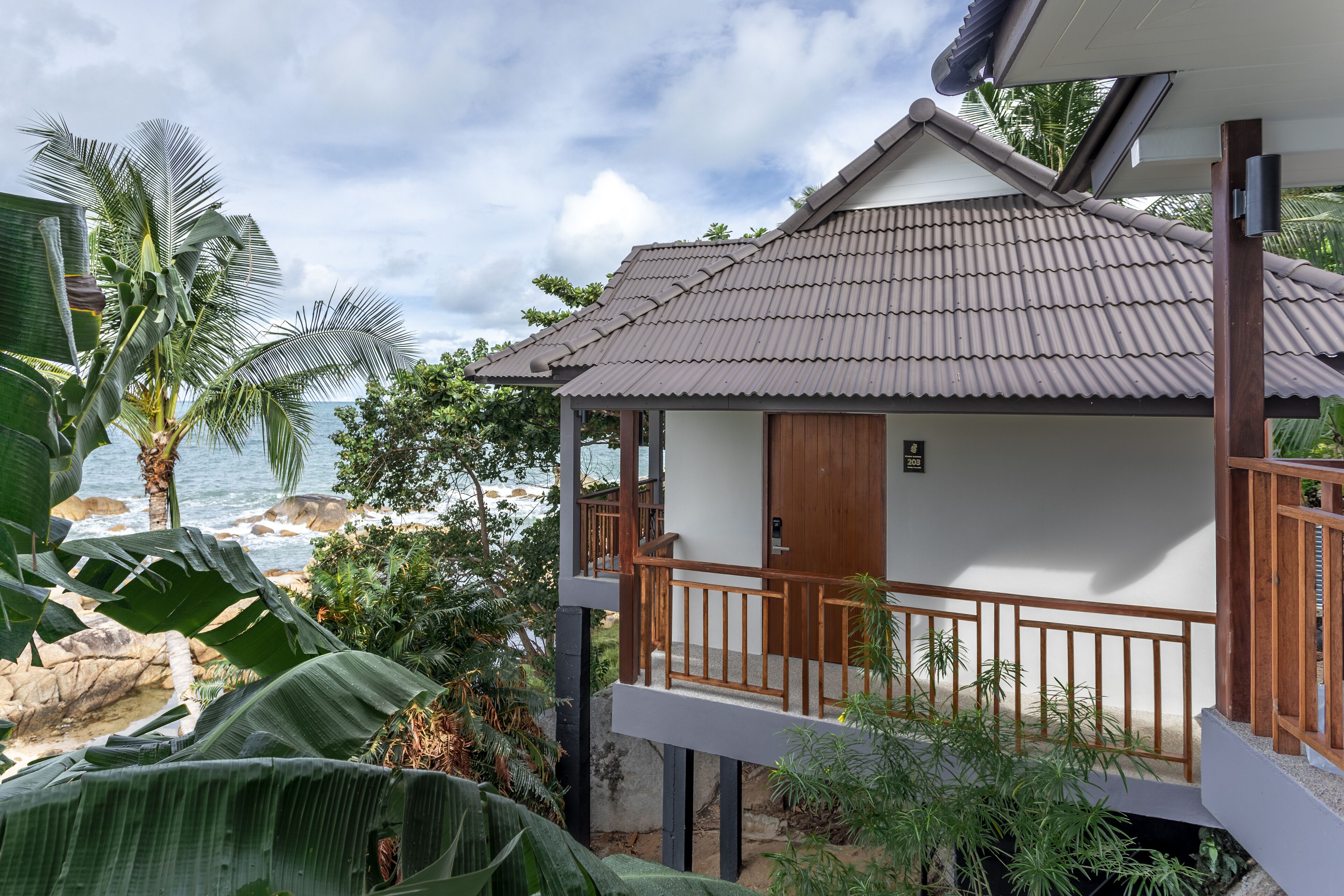 A two-story building with a balcony, a wooden door, and a view of the ocean.