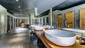 Un baño moderno con lavamanos grandes, armarios de madera y techo de hormigón.