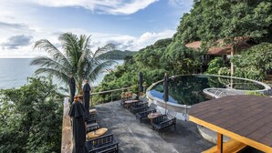 Un espacio al aire libre con mesas y sillas, una piscina y vista al mar.