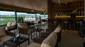 A spacious outdoor seating area with wicker furniture and a bar with a view of the city. - Bayleaf Inn (Port Blair)