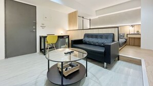 Ein modernes Wohnzimmer mit einem Glastisch, einem schwarzen Sofa und einem gelben Sessel.