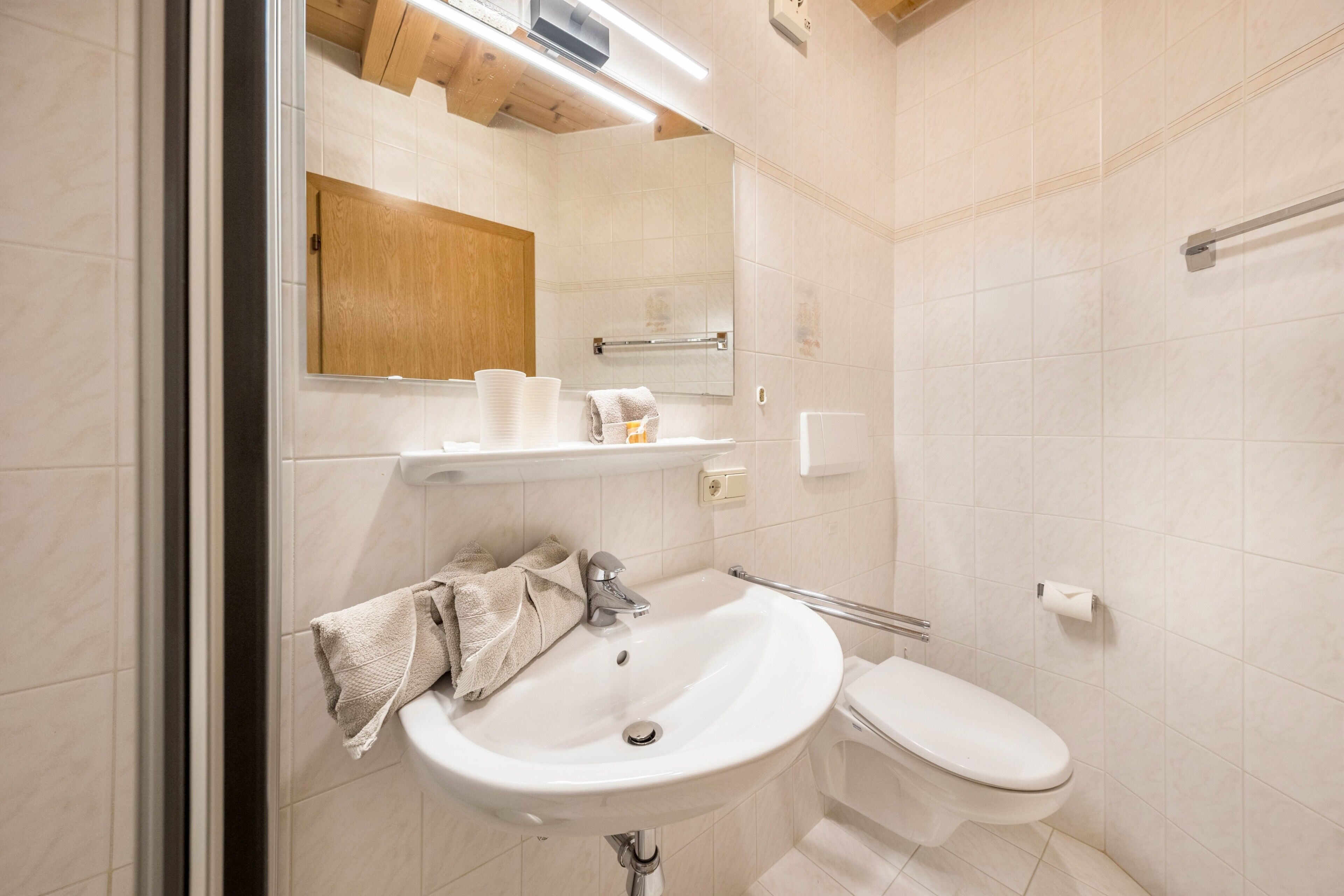 Ein Badezimmer mit Waschbecken, Toilette, Spiegel und Handtuchhalter.